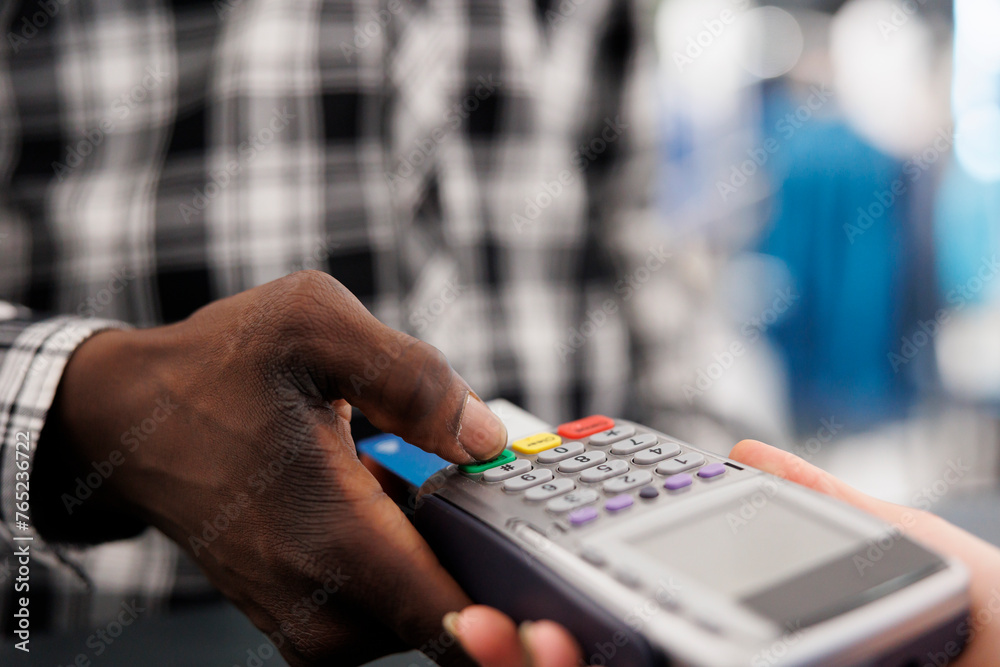 African american client introducing credit card detalis on pos to pay for stylish clothes, making contactless payment. Shopaholic man buying fashionable items for formal wear in boutique. Close up African american client introducing credit card detalis on pos to pay for stylish clothes, making contactless payment. Shopaholic man buying fashionable items for formal wear in boutique. Close up