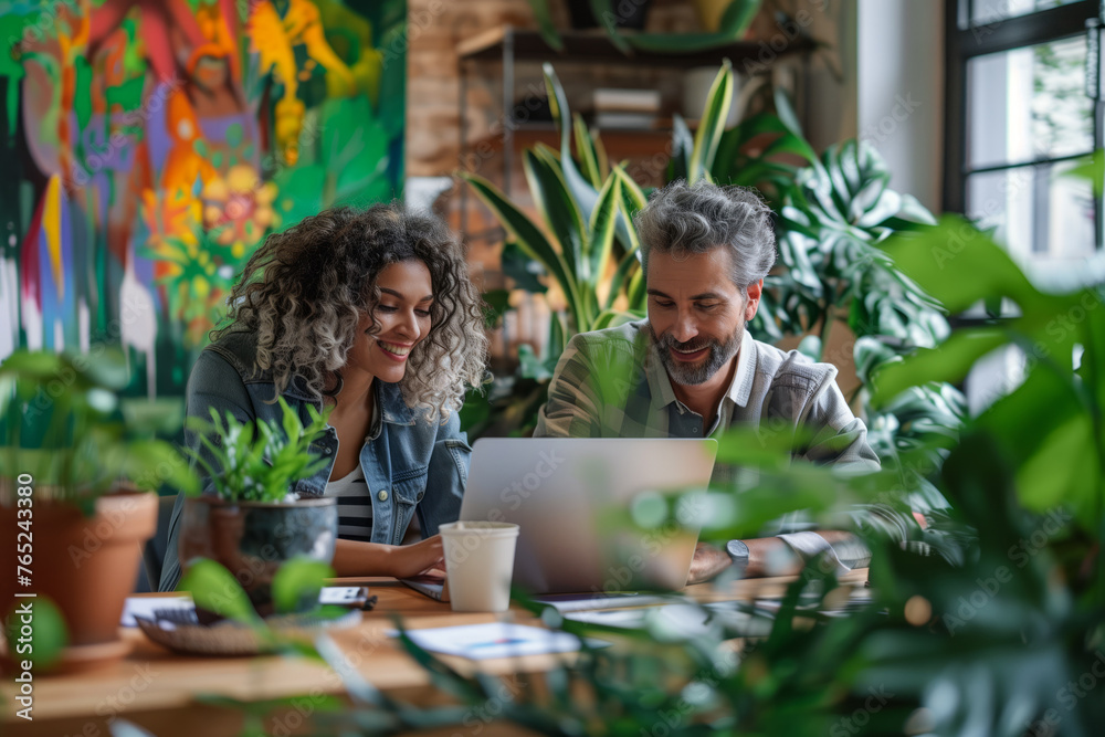 Smiling young woman and middle-aged man with laptop in a vibrant cafe with lush green plants, concept of coworking, mentorship, and urban gardening Smiling young woman and middle-aged man with laptop in a vibrant cafe with lush green plants, concept of coworking, mentorship, and urban gardening
