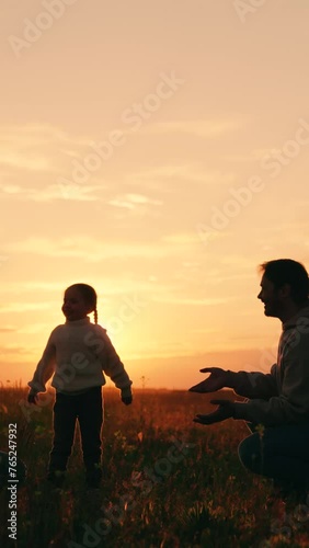 Child throws ball to mom and dad in sunshine. Mom dad child playing ball at sunset in park. Happy family. Children active games. Family walk outdoors. Parents and daughter have carefree fun in nature photo