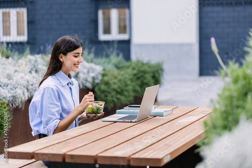 Happy student woman studying online using laptop outside at university campus. Education concept.