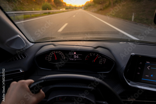 Driver view to the speedometer at 94 kmh or 94 mph, on a road blurred in motion. Sunset view from inside car from drivers POV to the road landscape.