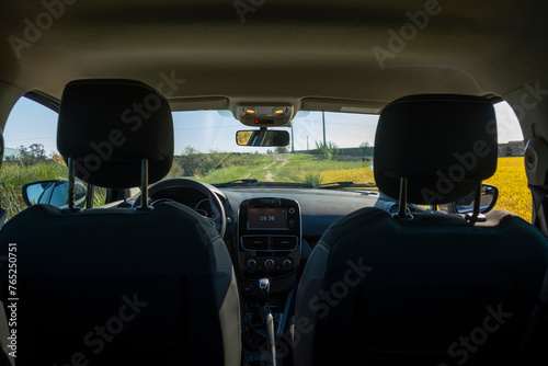 The interior of an empty car in the middle of countryside. View from the back seat.