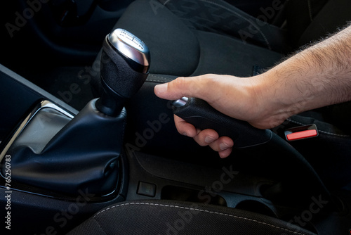 Close up of a man's hand tightens the manual handbrake on the car