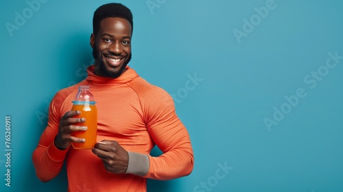 black athletic guy smiling and holding a glass of sports drink on a studio background