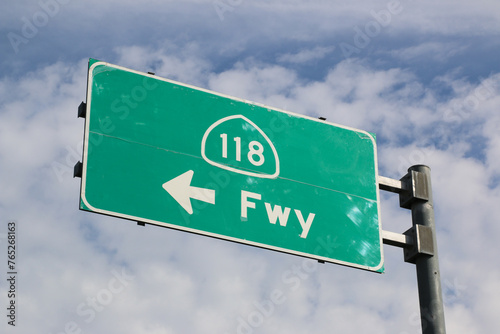 118 freeway sign against a blue sky with clouds