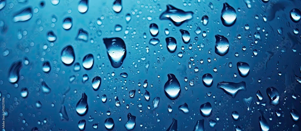 A close-up image of water droplets on a window glass against a vibrant blue background