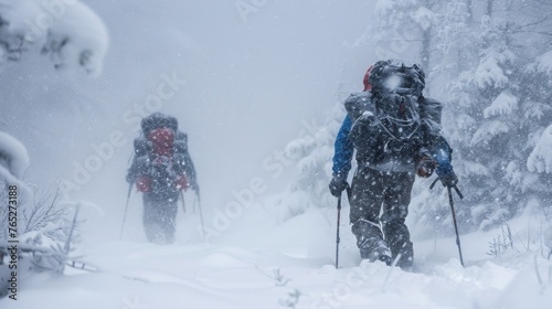Two hikers bundled in heavy jackets and backpacks struggle to keep their footing as a sudden snowstorm engulfs them. Trees are ly visible through the thick veil of swirling