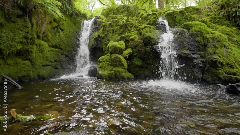 Two waterfalls in slow motion water crashing over rocks in woodland Two waterfalls in slow motion water crashing over rocks in woodland