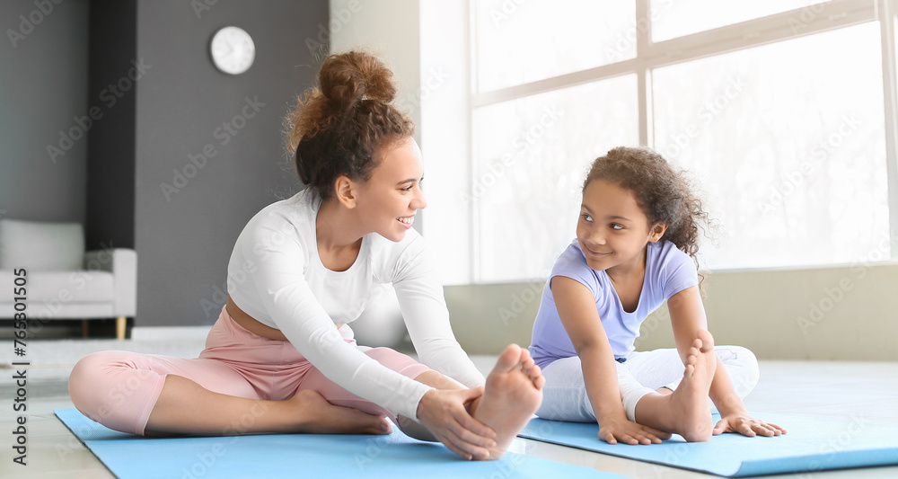 African-American little girl with her mother practicing yoga at home African-American little girl with her mother practicing yoga at home
