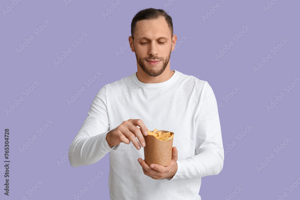 Young man with french fries on purple background Young man with french fries on purple background