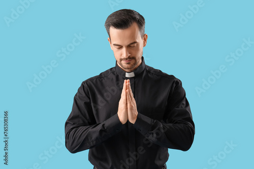 Portrait of male priest praying on blue background