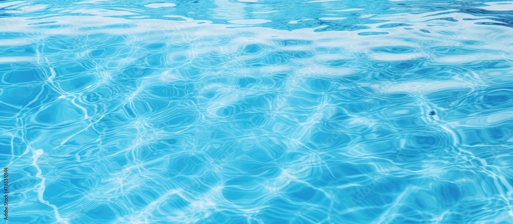A close up of the azure liquid in a swimming pool, showcasing the intricate pattern of wind waves under the electric blue sky