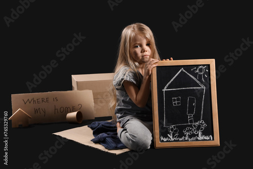 Slika na platnu Homeless little girl with picture of house on dark background