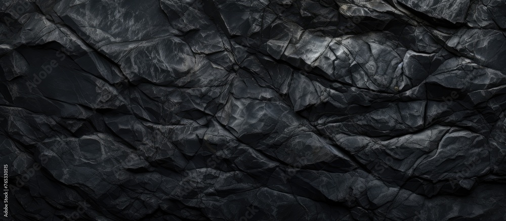 An image featuring a detailed view of a dark black rock wall with a solid black background