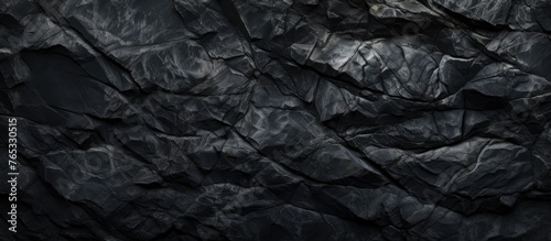 An image featuring a detailed view of a dark black rock wall with a solid black background