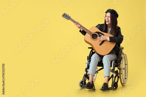 Female artist in wheelchair with guitar singing on yellow background