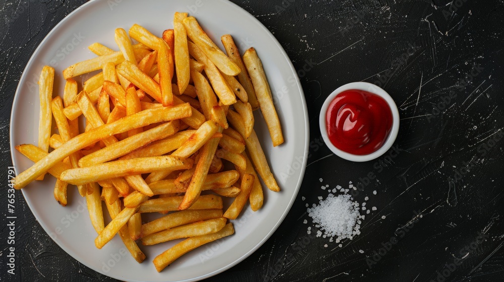 Homemade French Fries with Ketchup, Salt and Pepper on a white plate on a black background, top view. Copy space. Homemade French Fries with Ketchup, Salt and Pepper on a white plate on a black background, top view. Copy space.
