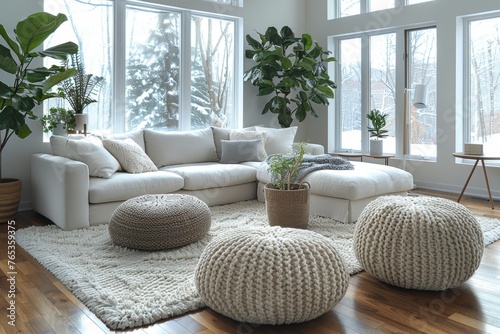A spacious, snowy view through large windows complementing a modern white sofa and soft pouffes in a clean living room. photo