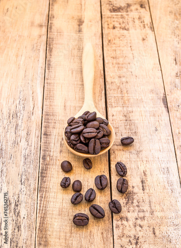 Coffee beans in wooden spoon on wooden background