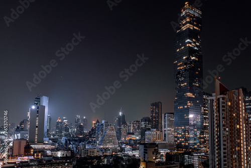 The breathtaking view of Silom District illuminated at night, captured from a rooftop vantage point in Bangkok, Thailand