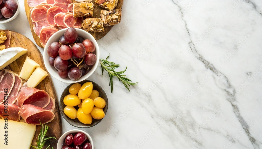 variety of charcuterie cheeses meats and appetizers overhead view side border on a white marble background with copy space