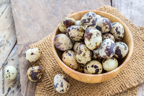 Quail eggs in wooden bowl on a wooden table