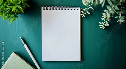 A blank white notebook for taking notes is placed on a green tabletop. view from above
