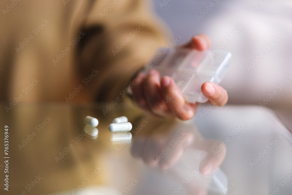 Closeup image of a woman holding pills box with pills on the table