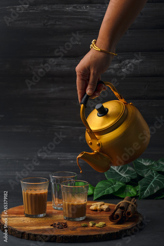 Fresh milk masala tea or Indian Kadak Chai.  Herbal tea in glass cups. Locally called mini cutting chai or cutting chai or masala chai. Indian chai in glass cups with metal kettle and other masalas 