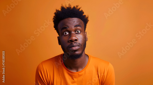 African American man in orange top reflects inner conflict and confusion  ideal for identity exploration themes.