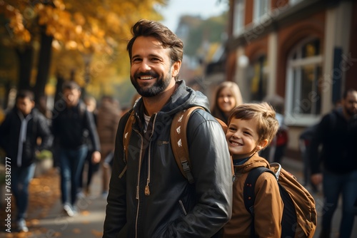 Schoolboy looking at father with smile while going with dad to first grade in school on sunny autumn day