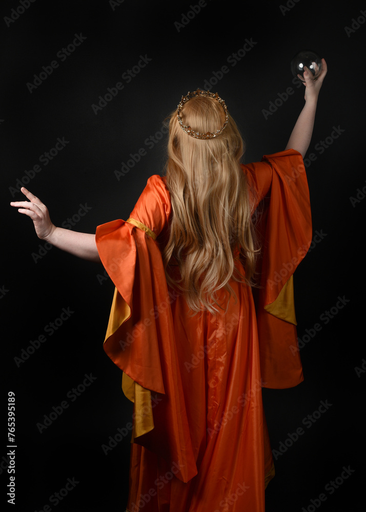 Obraz premium close up portrait of plus sized blonde woman, wearing historical medieval fantasy gown, crowned royal queen. posing holding magic crystal seer orb, isolated dark black studio background.