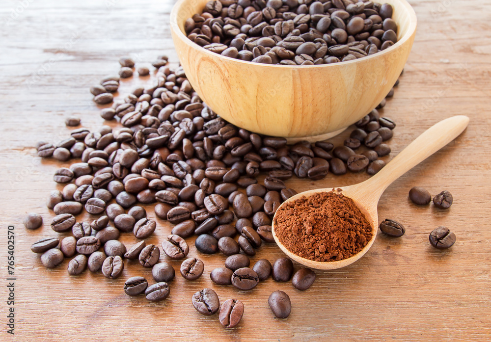 Fototapeta premium Coffee powder in wooden spoon and coffee beans on wooden table