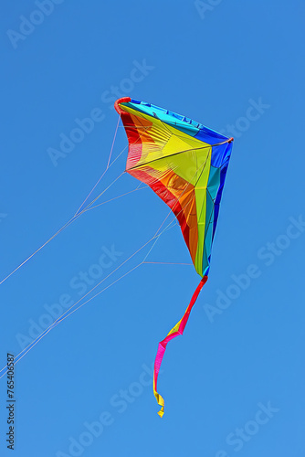 Rainbow-colored kite flying in a clear blue sky