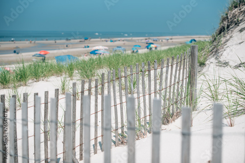 Wooden fence overlooking beach with dunes and beach umbrellas photo