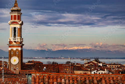 view of the roofs of venice with the mountains in the background