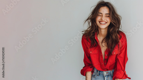 Brunette woman wearing red shirt smiling laugh out loud isolated on grey