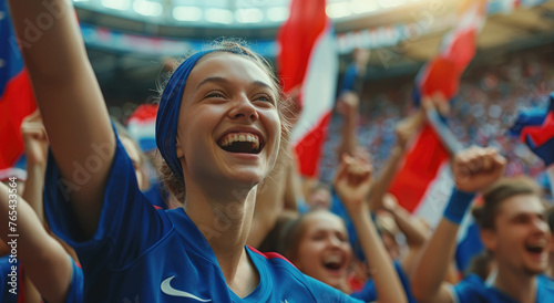 A young woman fan wearing a blue French team t-shirt cheering with her friends at the stadium © Kien