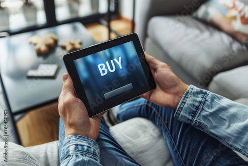 Buy stocks online concept image with a person holding a tablet with word Buy on screen representing an investor buying stocks or goods on the web from home photo