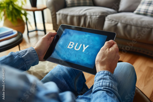 Buy stocks online concept image with a person holding a tablet with word Buy on screen representing an investor buying stocks or goods on the web from home photo