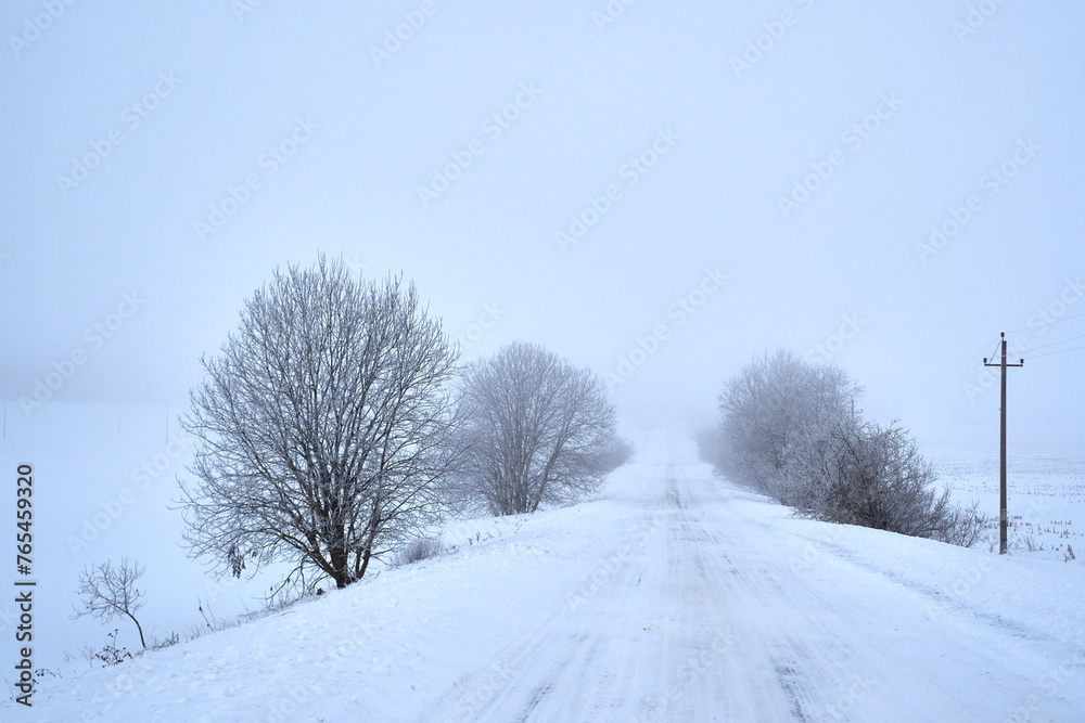 Rural winter landscape at dawn. Country road covered with snow Rural winter landscape at dawn. Country road covered with snow