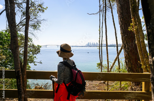 Woman enjoying the view of Auckland Harbour Bridge and Sky Tower from Kauri Point Centennial loop track. Auckland. photo