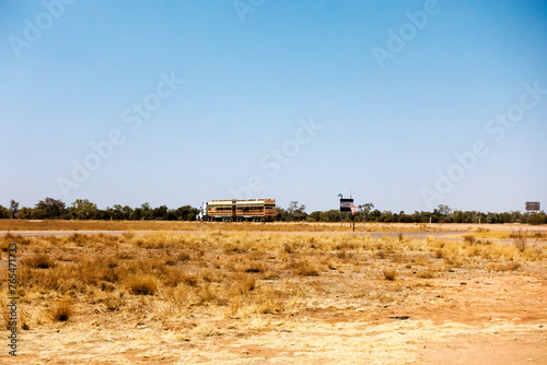 Road train and dry grass  in a flat dry desert landscape near Boulia in Outback Queensland, Australia