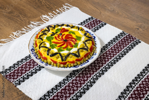 Traditional Romanian boeuf (beef) salad decorated for Christmas or Easter with a traditional towel on a wooden table