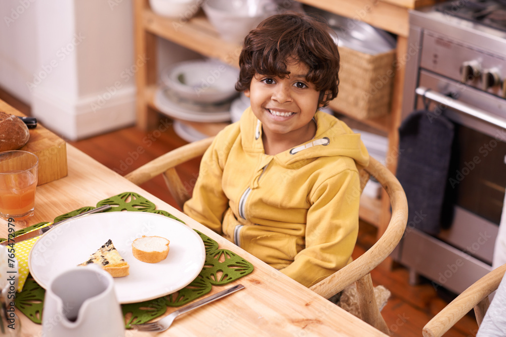 Happy boy, portrait and relax with meal for dinner, snack or starter in the kitchen at home. Face of little child or hungry kid with smile in happiness for plate, dish or serving at dining room table