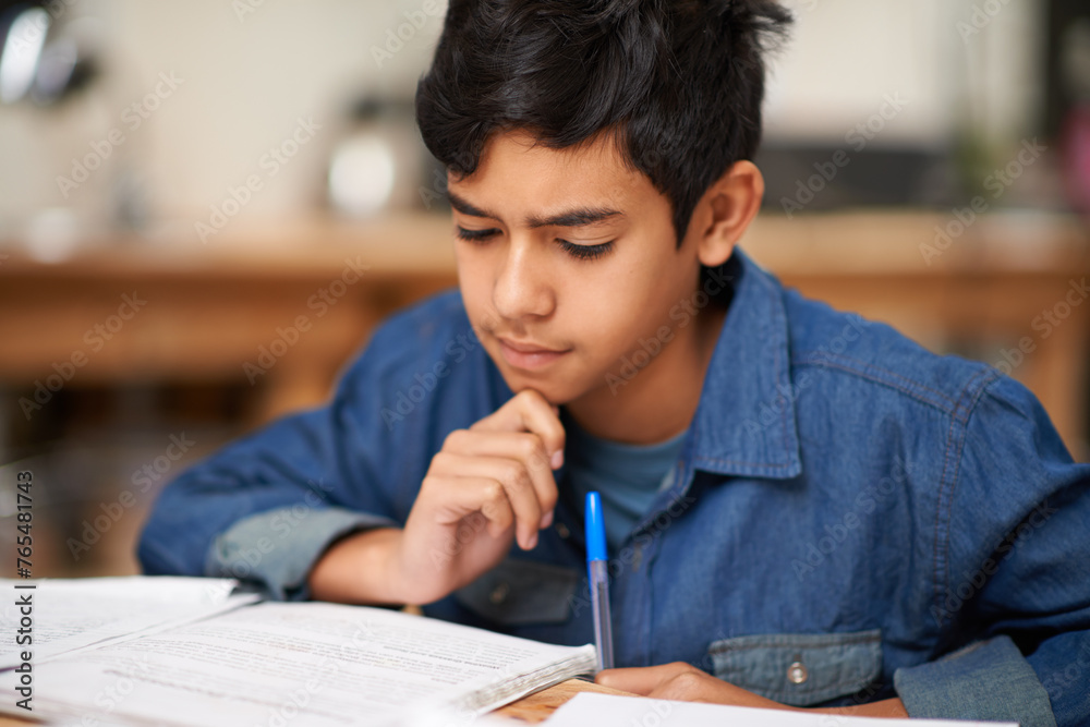 Student, boy and reading in home for study with thinking, problem solving and homework assessment by table. Child, education or knowledge with books in dining room for concentration on school project Student, boy and reading in home for study with thinking, problem solving and homework assessment by table. Child, education or knowledge with books in dining room for concentration on school project