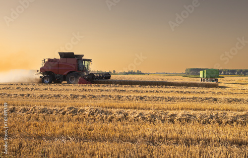 Harvester working in wheatfield at sunset. © Dusan Kostic