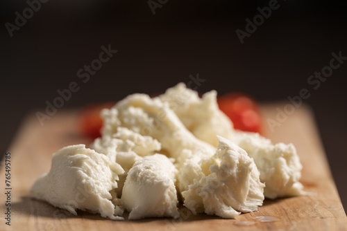 Torn mozzarella with tomatoes for salad on wood board