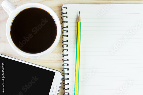 Smart phone and open notebook on wooden table