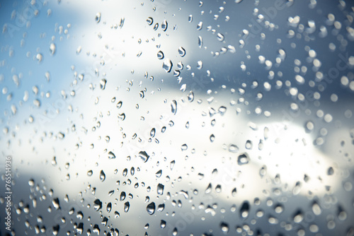 Kontrast der Elemente: Regentropfen an der Fensterscheibe vor sonnendurchflutetem Himmel